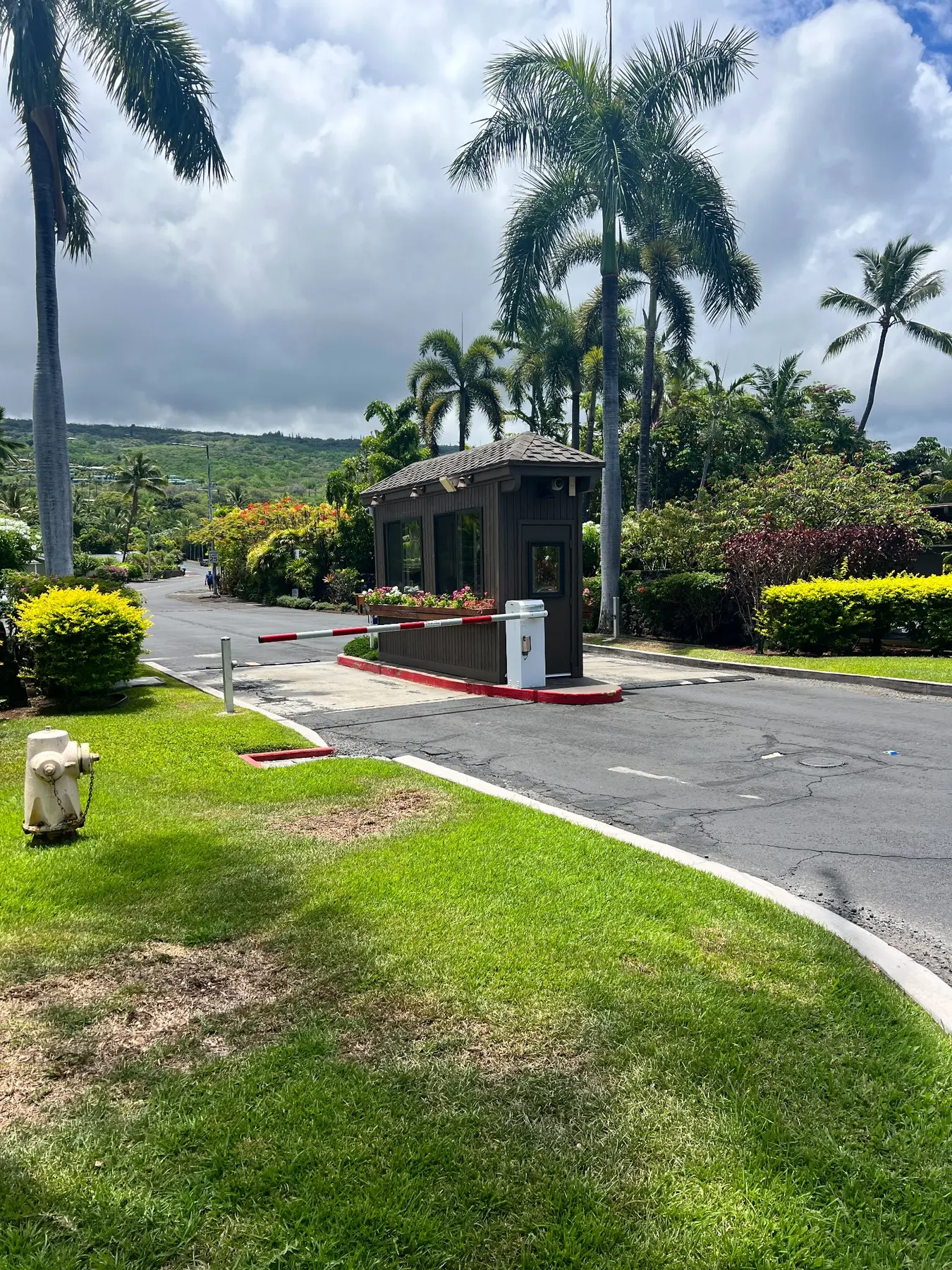 Guardhouse and gated entrance to Kanaloa at Kona surrounded by palm trees